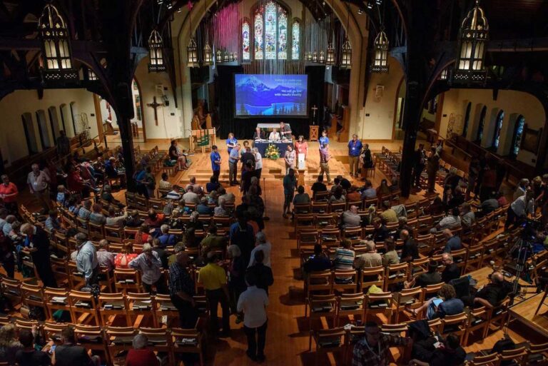 Overview of a cathedral under spotlights with people watching an election process.